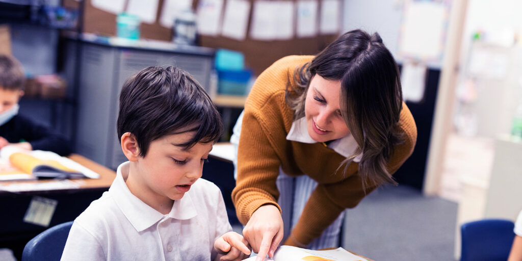 Teacher working with a student in a classroom.