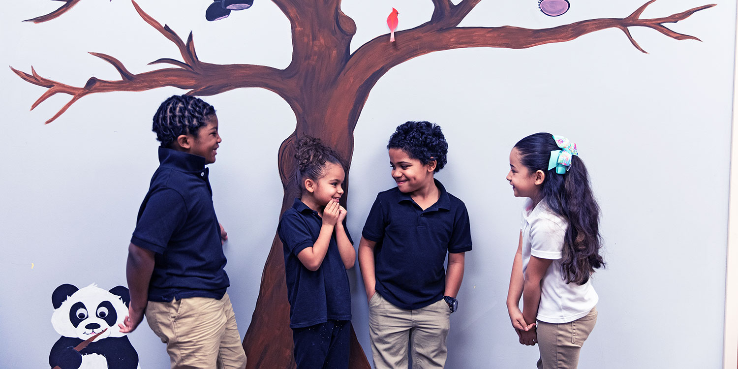 Smiling students standing in front of a wall mural.